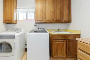 Washroom featuring independent washer and dryer and cabinet space