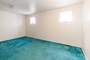 Carpeted spare room featuring baseboards and a textured ceiling