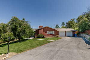 Ranch-style home with brick siding, a garage, asphalt driveway, and a chimney