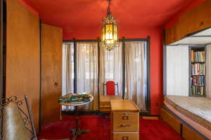 Carpeted bed room featuring a chandelier and healthy amount of natural light, and built-ins