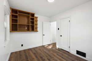 Unfurnished bedroom featuring baseboards and dark wood-type flooring