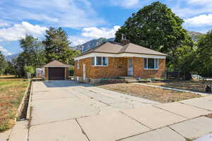 Bungalow-style house with brick siding, an outdoor structure, a garage, and a mountain view
