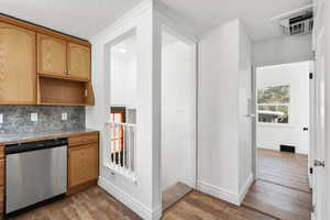 Kitchen featuring dishwasher, wood finished floors, and tasteful backsplash