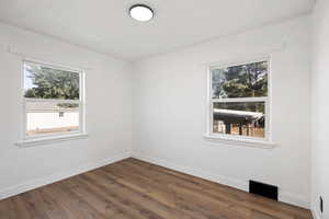 Unfurnished room featuring plenty of natural light and dark wood-style floors