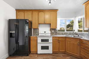 Kitchen with black fridge, range with two ovens, tasteful backsplash, dark wood-type flooring, and a textured ceiling