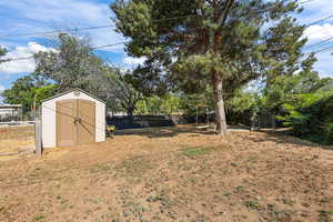 Fenced backyard featuring a storage shed
