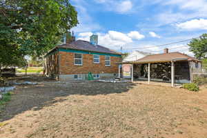 Back of house featuring a chimney, brick siding, a patio, and a yard
