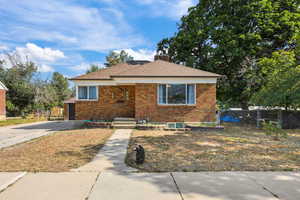 Bungalow-style home featuring brick siding, a chimney, and roof with shingles