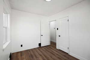 Unfurnished bedroom with dark wood finished floors and baseboards