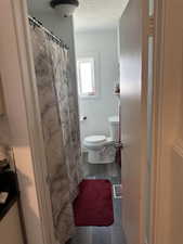 Bathroom with wood finished floors, a textured ceiling, and a shower with curtain