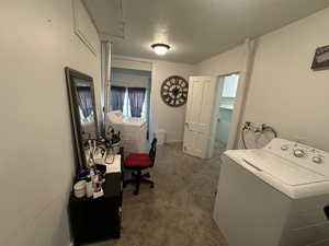 Carpeted home office with washer and dryer and a textured ceiling