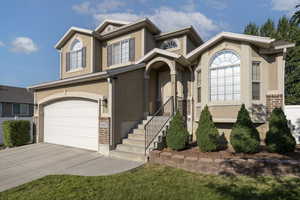 View of front of home featuring a garage, concrete driveway, stucco siding, and brick siding