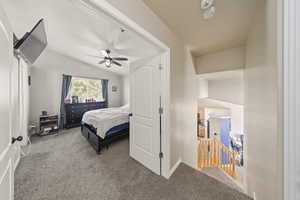 Carpeted bedroom with lofted ceiling and ceiling fan