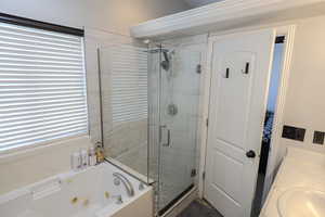 Bathroom with a jetted tub, a stall shower, and healthy amount of natural light