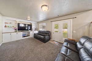 Living area featuring a textured ceiling and carpet flooring
