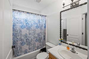 Bathroom featuring vanity and shower / bathtub combination with curtain