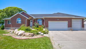 Ranch-style house featuring a garage, brick siding, driveway, a front lawn, and a shingled roof