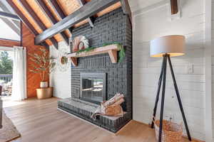 Living area with beam ceiling, plenty of natural light, wood finished floors, wooden walls, and a fireplace
