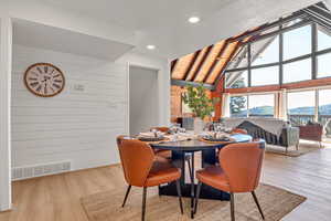 Dining area with wood walls, wood finished floors, high vaulted ceiling, and recessed lighting