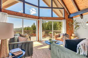 Living area featuring plenty of natural light, wood walls, high vaulted ceiling, and a wood ceiling with exposed beams