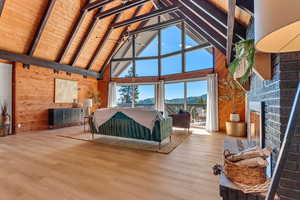 Living room featuring high vaulted ceiling, wood walls, wood finished floors, a fireplace, and a mountain view