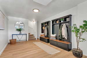 Mudroom featuring light wood-style floors and built in shelves