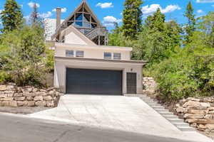 View of front facade with stairway, concrete driveway, a garage, and a chimney