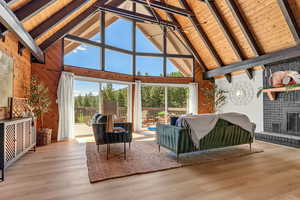 Living room featuring high vaulted ceiling, wooden walls, healthy amount of natural light, a wood ceiling with exposed beams, and wood finished floors