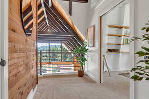 Corridor featuring lofted ceiling, carpet flooring, and wooden walls