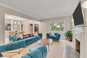 Living area featuring healthy amount of natural light, a fireplace with flush hearth, and crown molding