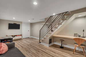 Living area with wood finished floors, recessed lighting, and stairs
