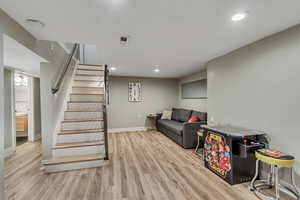 Living room with wood finished floors, stairs, and recessed lighting