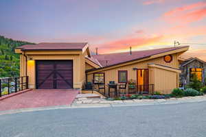 View of front of home featuring an attached garage, decorative driveway, and a shingled roof