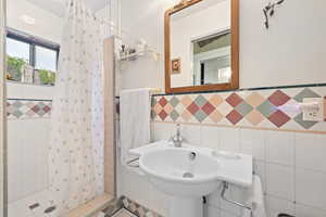 Full bathroom featuring a shower stall and tile walls