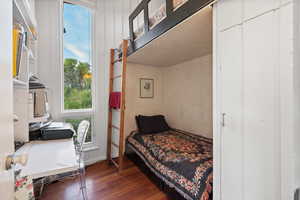 Bedroom featuring dark wood-type flooring, multiple windows, and an office area