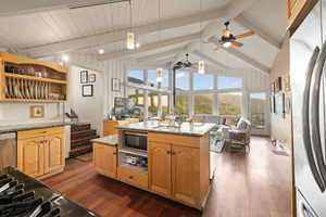 Kitchen featuring appliances with stainless steel finishes, dark wood-type flooring, light stone counters, a kitchen island with sink, and wood ceiling