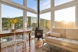 Sunroom featuring a wood stove, wood finished floors, and a mountain view