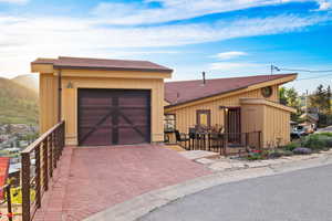 View of front of home featuring an attached garage, a shingled roof, and decorative driveway