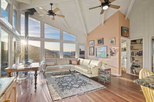 Living room featuring ceiling fan, high vaulted ceiling, wood finished floors, and beam ceiling