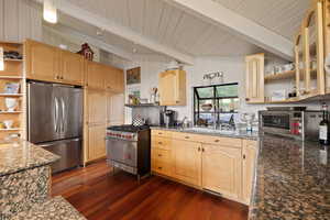 Kitchen featuring open shelves, appliances with stainless steel finishes, light brown cabinetry, dark stone countertops, and wooden ceiling