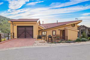 View of front facade with decorative driveway, a shingled roof, and a garage