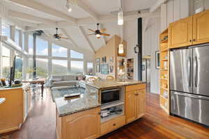 Kitchen featuring appliances with stainless steel finishes, open shelves, track lighting, dark wood-type flooring, and beamed ceiling