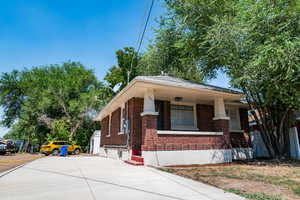 View of front of house featuring brick siding, concrete driveway, and covered porch
