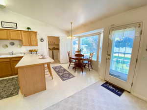Kitchen with washer and dryer, a peninsula, a chandelier, vaulted ceiling, and a kitchen bar