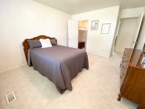 Bedroom featuring light colored carpet and a spacious closet