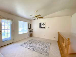 Carpeted empty room featuring ceiling fan and lofted ceiling