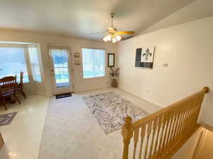 Entryway with carpet floors, ceiling fan, and vaulted ceiling