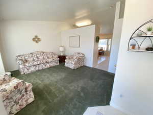 Living area featuring lofted ceiling and carpet flooring
