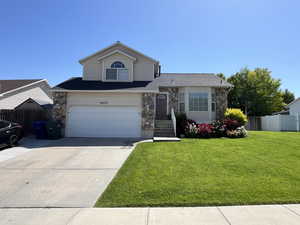 View of front of property with stone siding, driveway, an attached garage, and a shingled roof