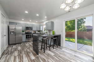 Kitchen featuring stainless steel appliances, gray cabinetry, dark countertops, healthy amount of natural light, and recessed lighting
